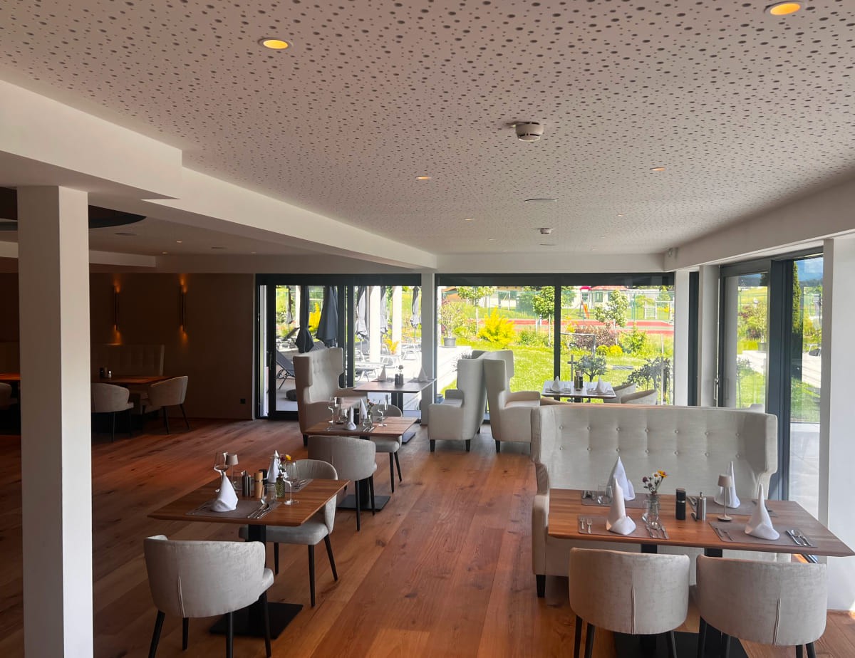 Elegantes Restaurant im Landhaus Ramsau mit Holzfu&szlig;boden und gro&szlig;en Fenstern mit Blick ins Gr&uuml;ne