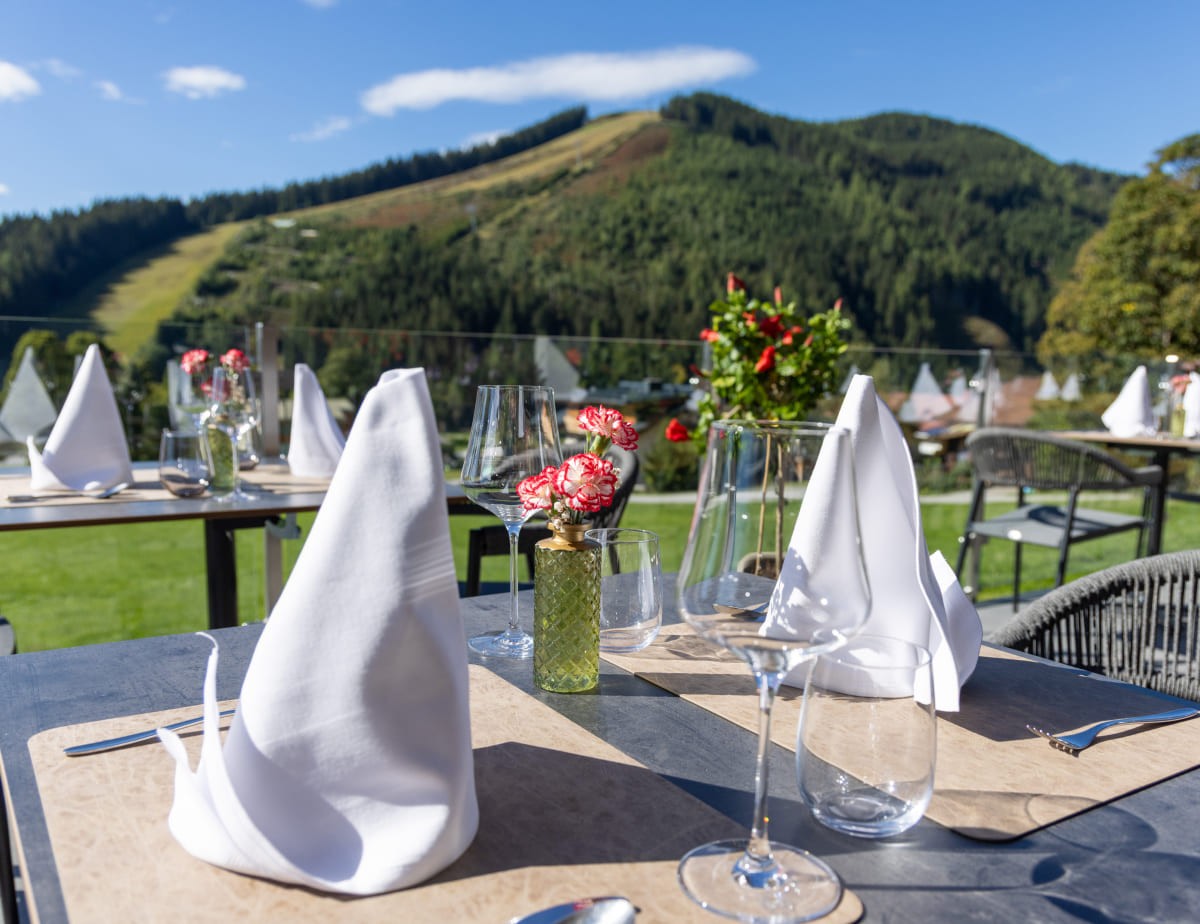 Gedeckte Tische auf einer Terrasse mit Bergblick im Hintergrund