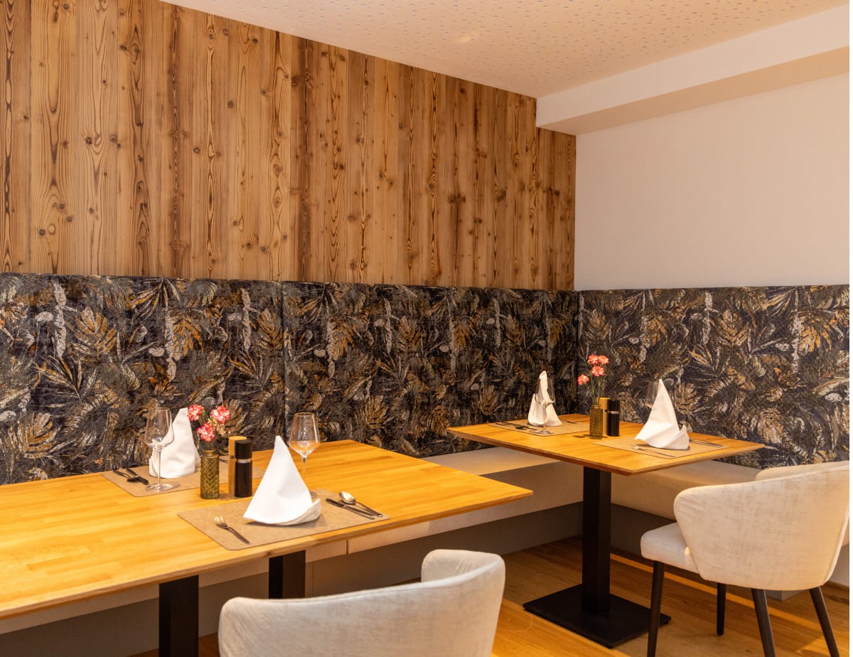 In einem gem&uuml;tlichen Restaurant stehen vier Tische mit wei&szlig;en Servietten und Blumen geschm&uuml;ckt