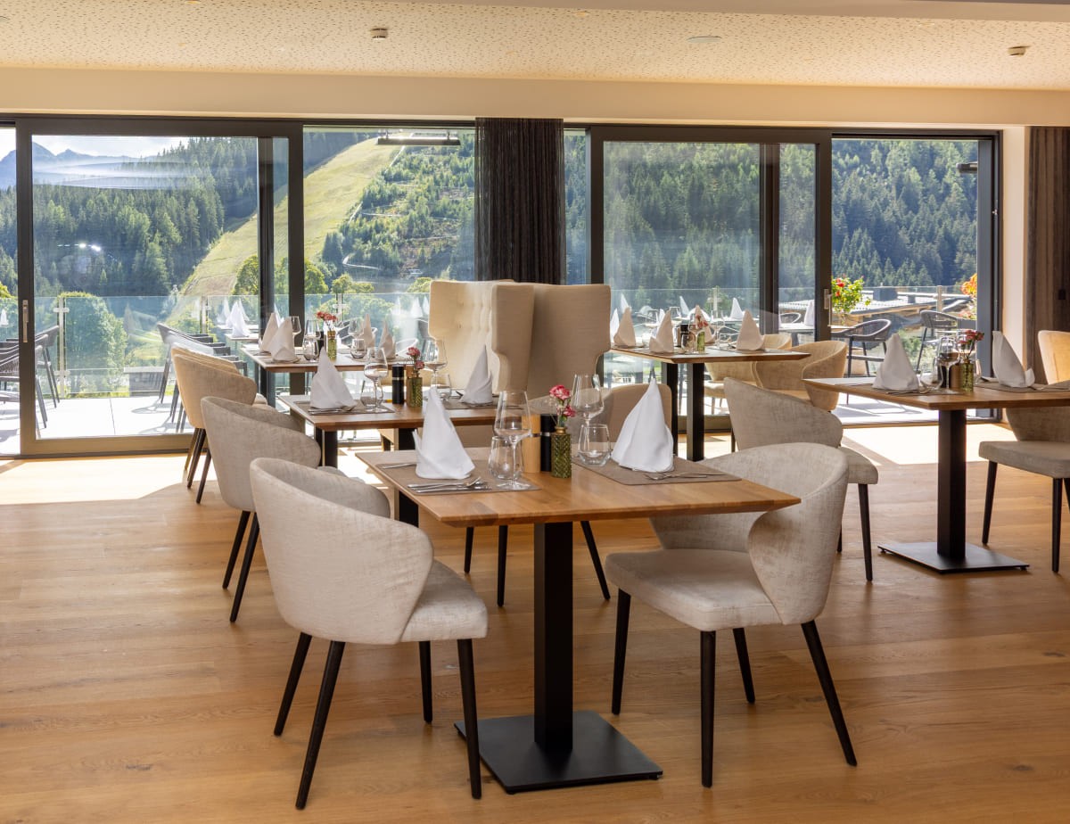 Elegantes Restaurant mit Bergblick, gedeckten Tischen und gro&szlig;en Fenstern