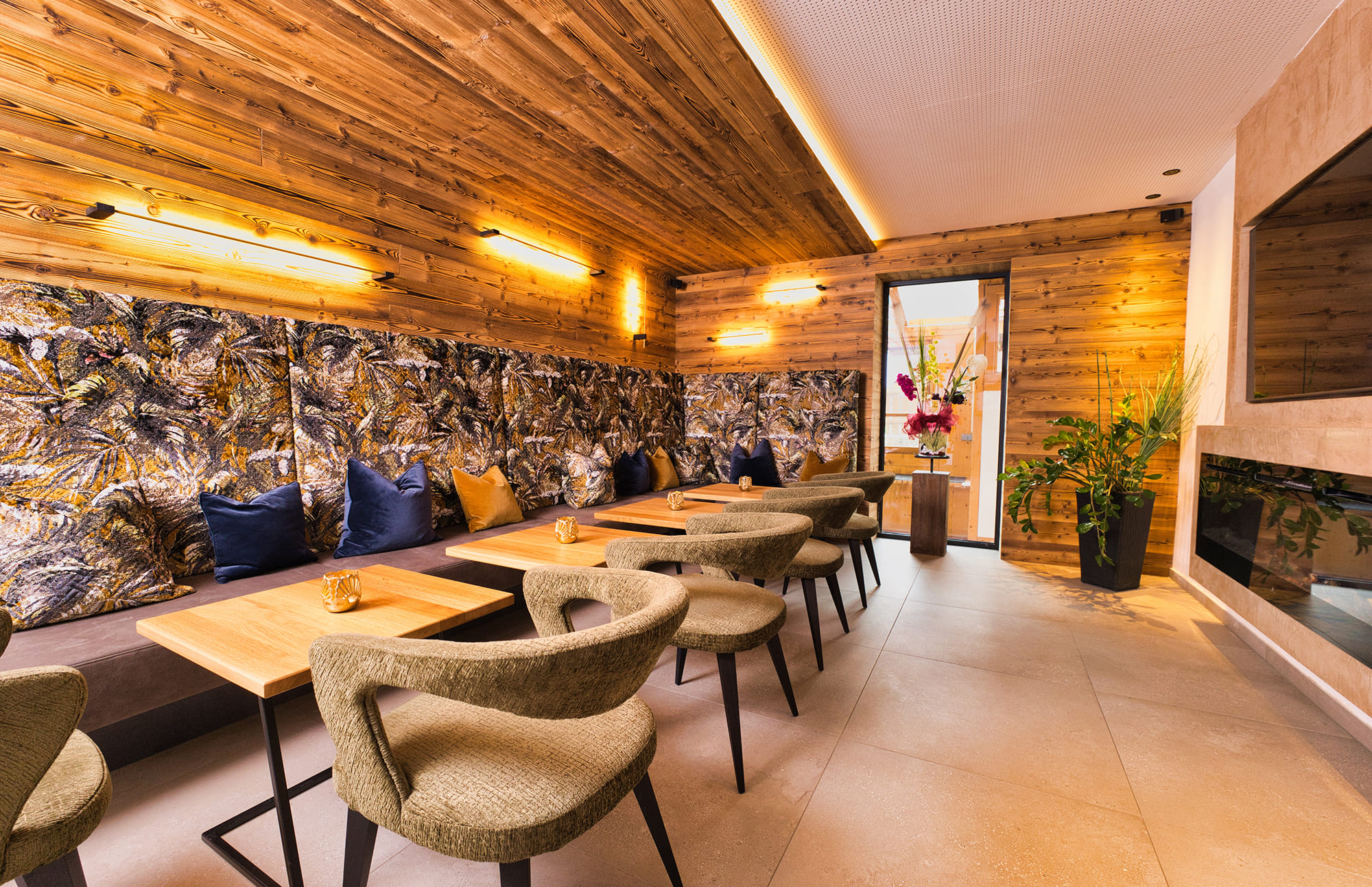 Gemütlicher Restaurantbereich mit Holzwänden, gepolsterten Bänken und modernen Stühlen