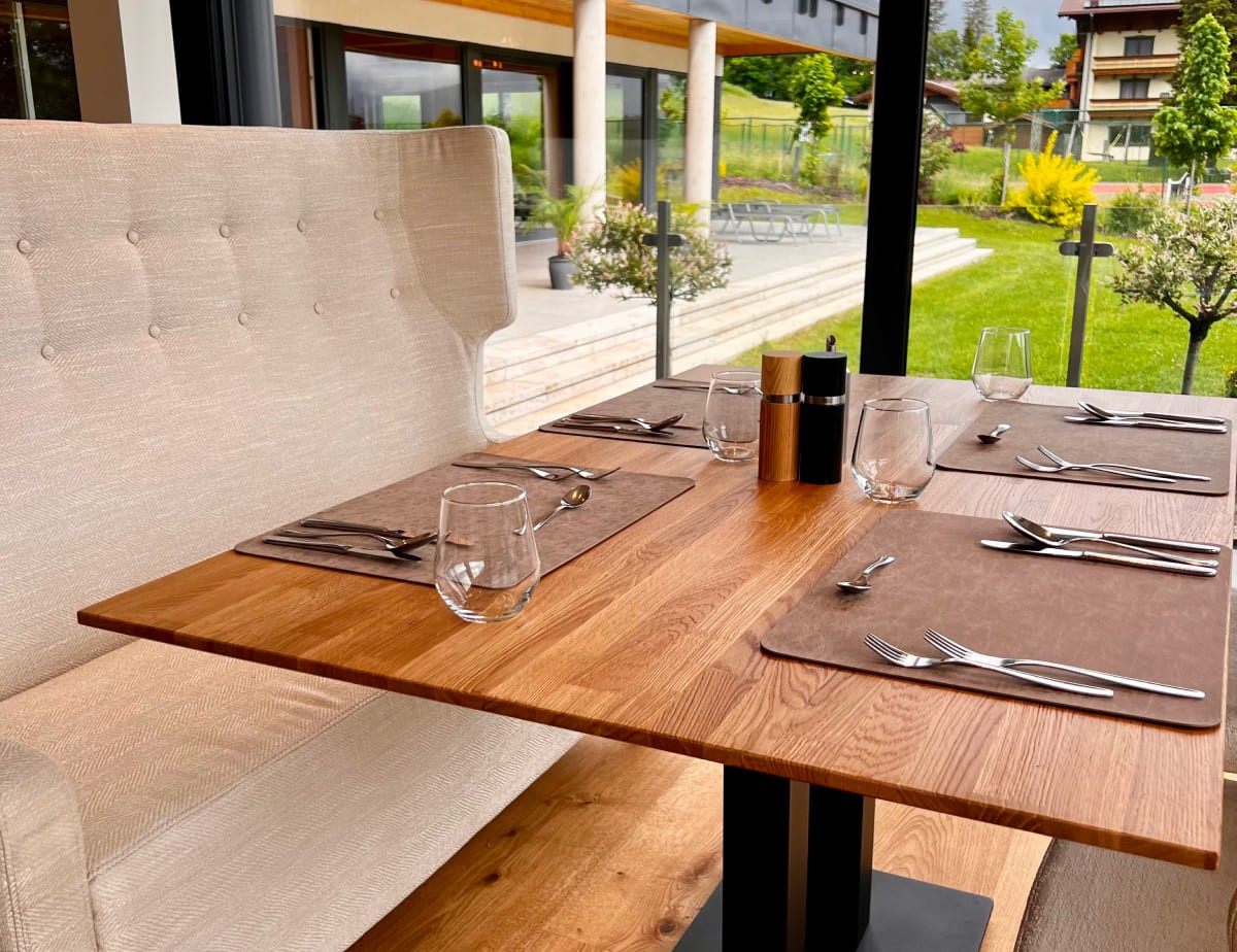 Gedeckter Tisch im Restaurant vom Hotel Landhaus Ramsau mit Blick auf einen gr&uuml;nen Garten