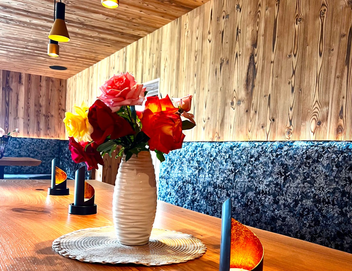 Ein Blumenstrau&szlig; in einer Vase auf einem Holztisch mit Wandverkleidung im Hintergrund