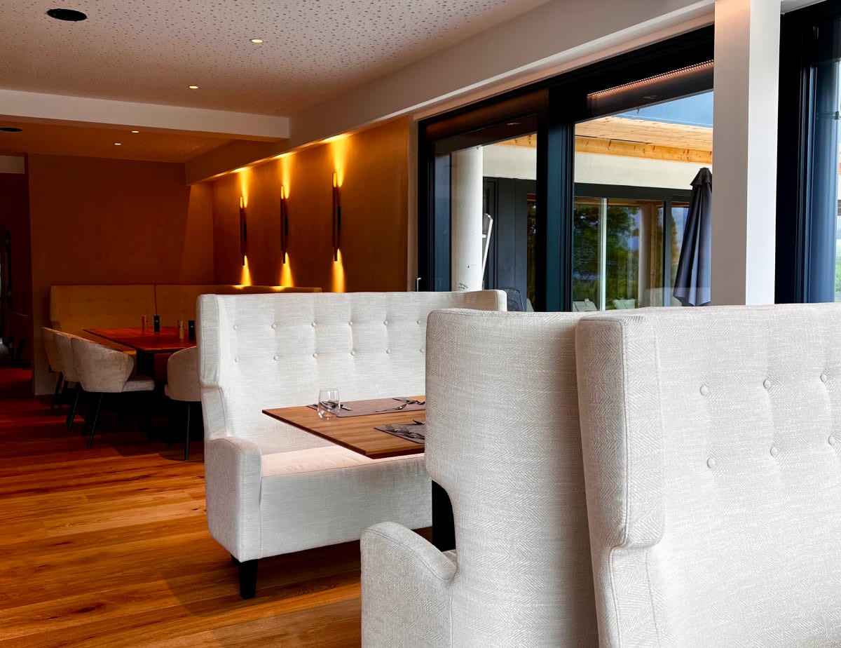 Modernes Restaurant im Landhaus Ramsau mit eleganten Sofas und Holzb&ouml;den