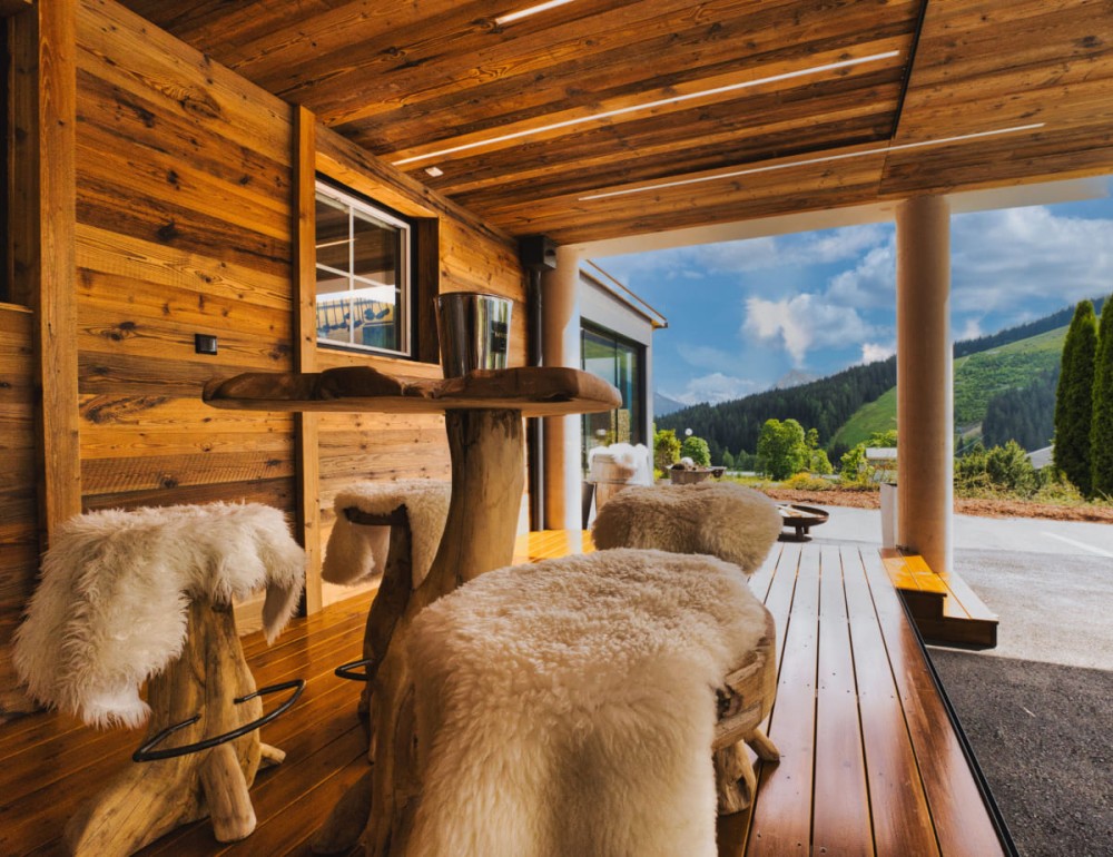Gem&uuml;tliche Terrasse mit Holzdekor, Fellbez&uuml;gen und malerischem Bergblick der Dachstein Region im Hintergrund