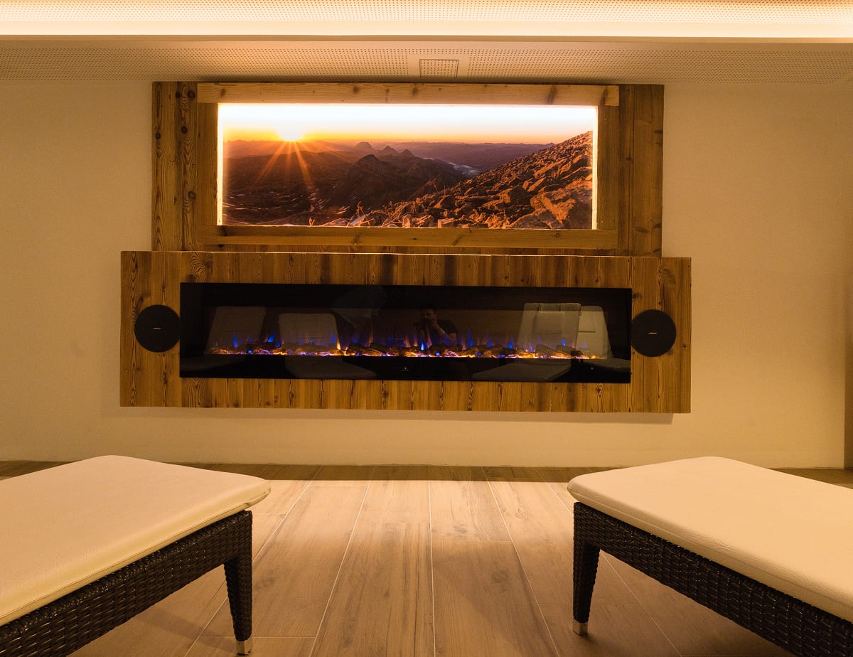 Gem&uuml;tliches Zimmer mit Kamin und Sonnenuntergangsbild an der Wand