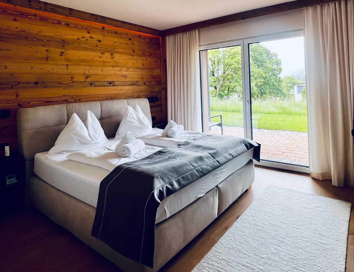 Gem&uuml;tliches Schlafzimmer mit Doppelbett und Fenster mit Blick auf gr&uuml;nen Garten