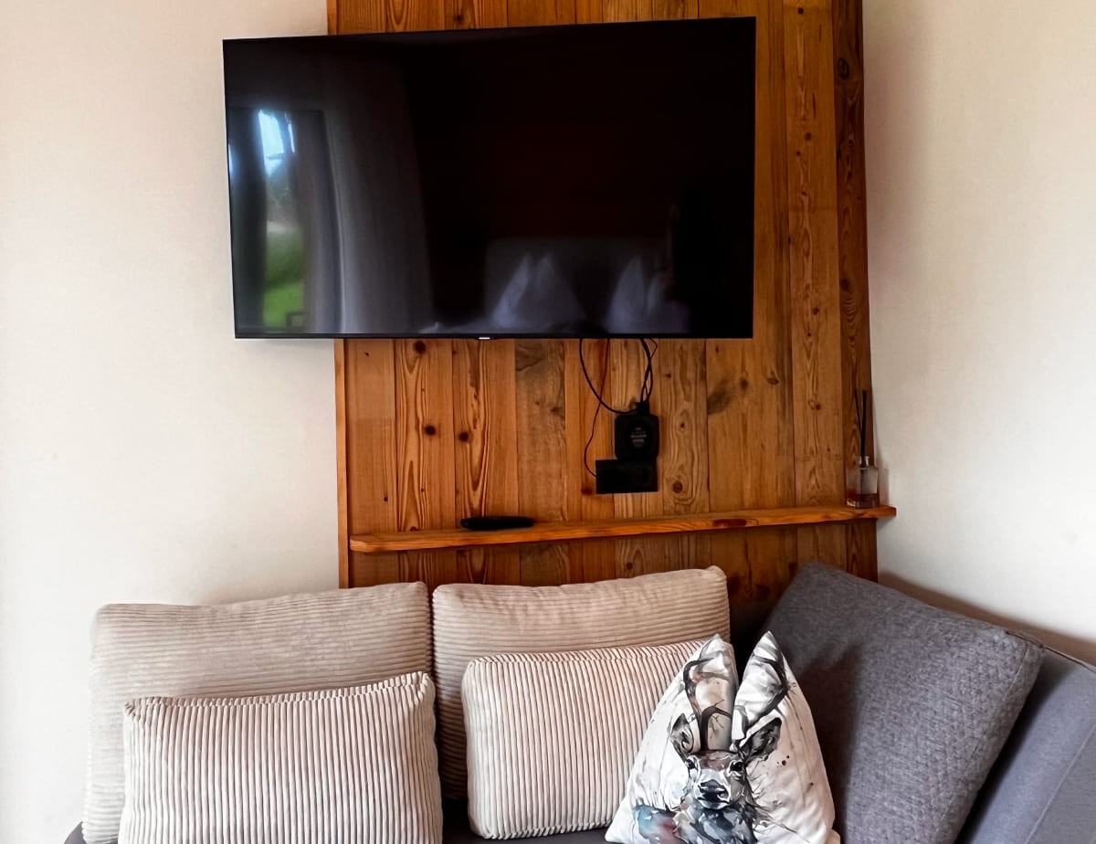 Wand-TV &uuml;ber Sofaecke mit Kissen in neutralen T&ouml;nen