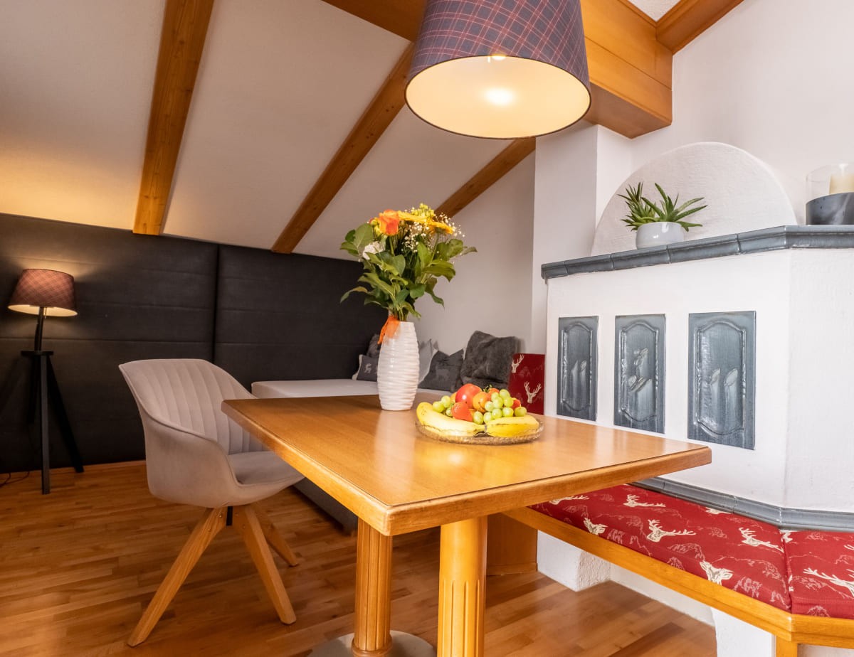 Holztisch mit Blumenstrau&szlig; und Obstteller in gem&uuml;tlichem Wohnraum im Appartement