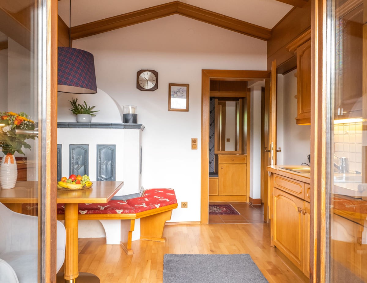 Gem&uuml;tliches Wohnzimmer im Appartement mit Holzm&ouml;beln, rotem Sitzpolster und Obstschale