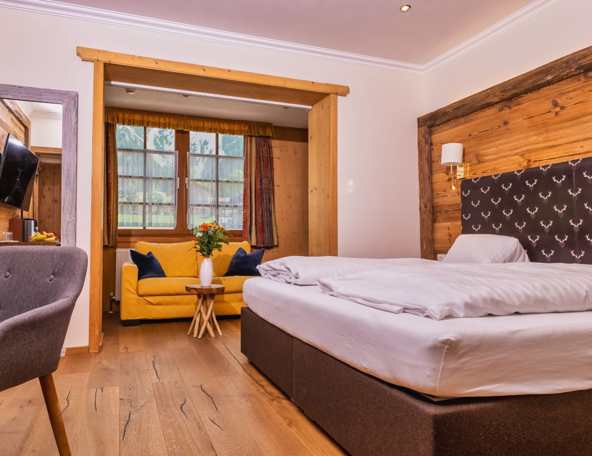 Gem&uuml;tliches Doppelzimmer mit Dachsteinblick mit Holzw&auml;nden, gelbem Sofa und gro&szlig;em Fenster