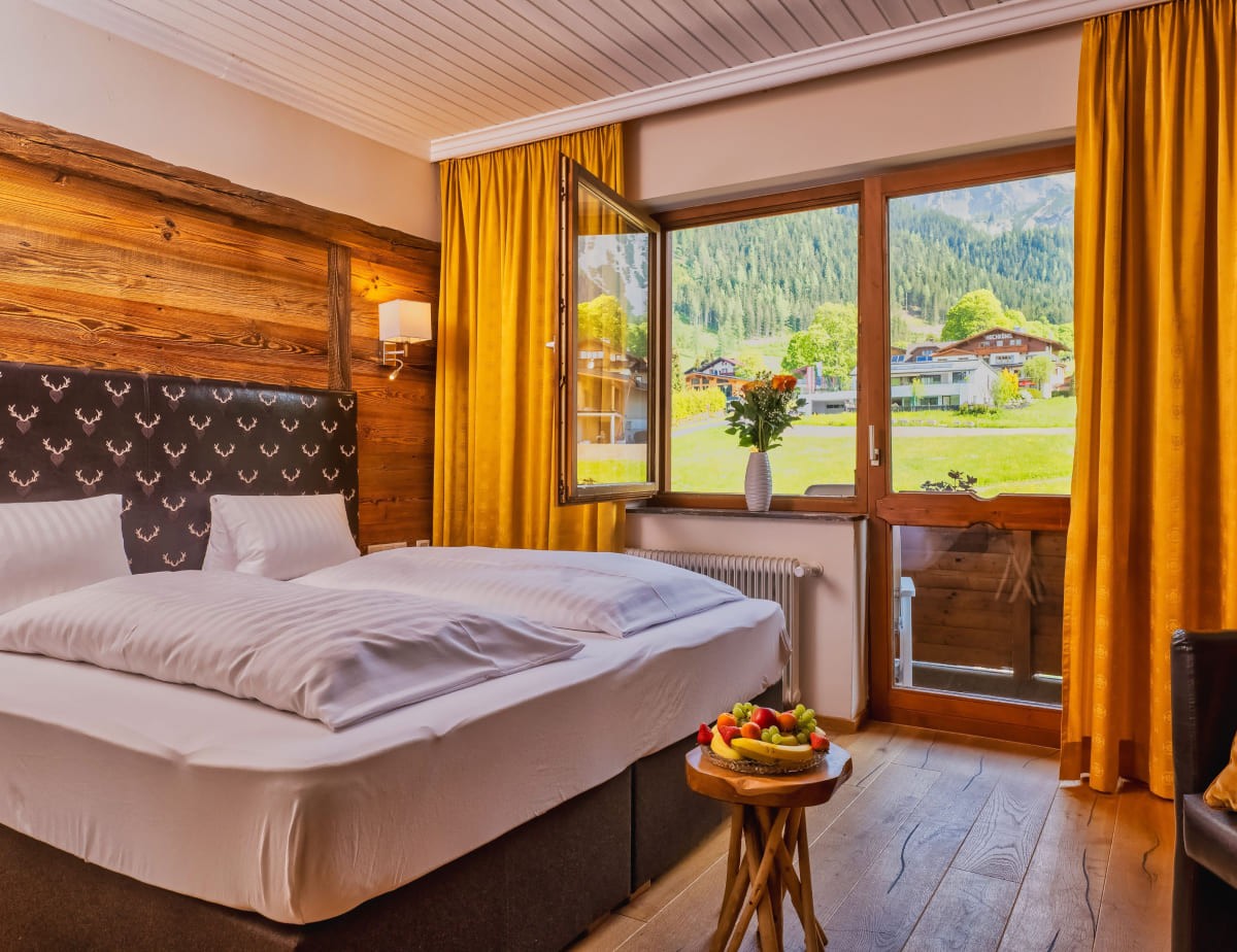 Gem&uuml;tliches Familienzimmer mit Holzdetails, gro&szlig;em Fenster und Blick auf die Berge