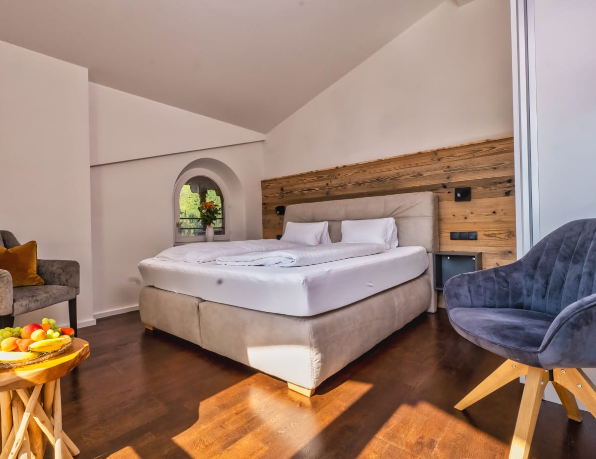 Helles Schlafzimmer mit Doppelbett, Holzdetails und gem&uuml;tlichen Sesseln