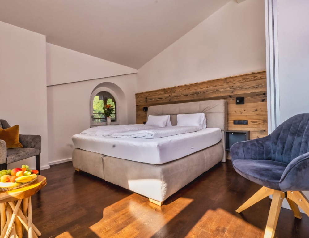 Helles Schlafzimmer mit Holzdetails, einem gro&szlig;en Bett und einem kleinen Tisch mit Obst